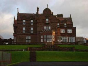 a large brick building on top of a green field at Adamton Country House Hotel in Prestwick