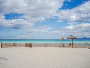 una playa con dos sombrillas de paja y el océano en Apartment Los Girasoles by Interhome, en Alcudia