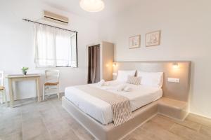 a bedroom with a large white bed and a table at Porto Bello Tinos in Agios Ioannis