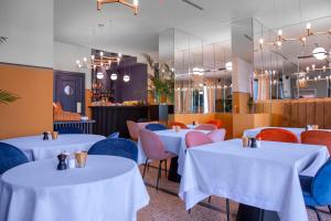 un restaurant avec des tables blanches et des chaises colorées dans l'établissement Zemeli Boutique Hotel by DNT Group, à Tbilissi