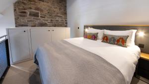 1 dormitorio con 1 cama grande con sábanas y almohadas blancas en Linton Collection - Blackfriars Lofts, en Edimburgo