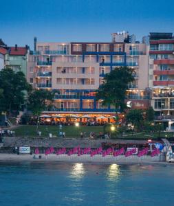 a large building with pink chairs in front of the water at Selena Hotel in Sozopol