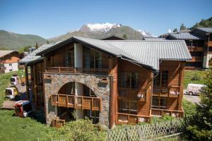a large log cabin with an archway in a yard at Résidence Aiguille Lodge in Les Deux Alpes