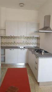 a kitchen with white cabinets and a red rug at Elba in relax in Rio Marina