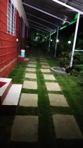a walkway in front of a building with grass at Vamoose Malvan Katta in Satara