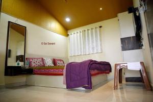 a room with a bed with a purple blanket on it at Vamoose Malvan Katta in Satara