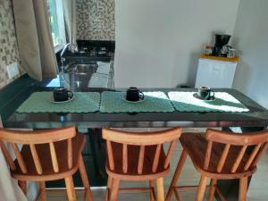 a kitchen with a table with two cups and two chairs at Chalés Vale dos Pássaros in Paraty