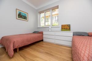 - une chambre avec 2 lits, une commode et 2 fenêtres dans l'établissement Vila prie jūros, à Palanga