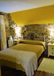 1 dormitorio con 2 camas y pared de piedra en Apartamentos Torre Villar, en Villar de Vildas