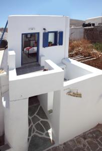 a white house with a mirror on the side at Margarita's Rooms in Chora Folegandros