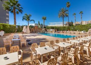 a restaurant with tables and chairs next to a swimming pool at Apartamentos La Era Park in Benidorm