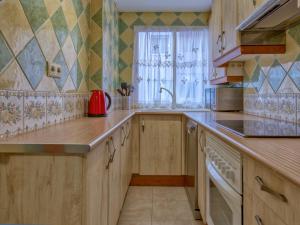 a kitchen with wooden cabinets and a sink and a window at Apartment Calpe Pueblo by Interhome in Calpe