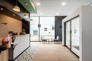 an office lobby with a desk and chairs at B&B HOTEL Cergy Saint Christophe in Cergy