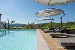 a swimming pool with two umbrellas and lounge chairs at La Rimbecca Greve in Chianti in Greve in Chianti