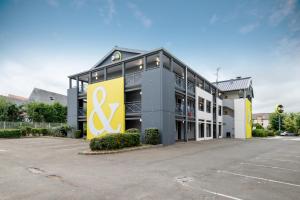 a large office building with a yellow and gray at B&B HOTEL Dieppe in Saint-Aubin-sur-Scie