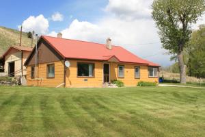 una casa amarilla con techo rojo y patio en Sportsman Lodge Melrose MT en Melrose