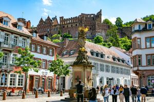 eine Gruppe von Menschen, die durch eine Stadt laufen mit einem Schloss im Hintergrund in der Unterkunft BS Luxury Suites in Heidelberg