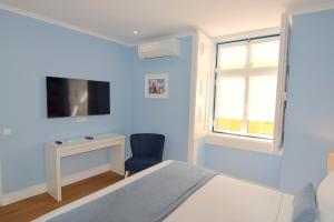 a blue bedroom with a bed and a window and a chair at Lx Flowers Apartments in Lisbon