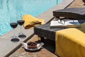 two glasses of wine and a book on a table next to a pool at La Rimbecca Greve in Chianti in Greve in Chianti