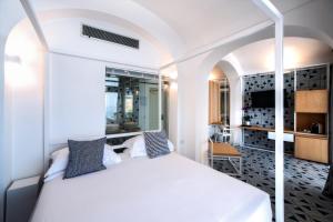 a bedroom with a white bed and a tv at Hotel Montemare in Positano