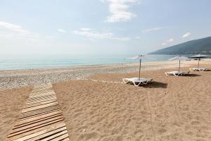 two beach chairs and umbrellas on a sandy beach at Old Gagra Hotel in Gagra