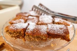 a glass plate with a piece of cake with powdered sugar at Porto Bello Tinos in Agios Ioannis