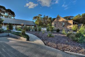 une ancienne maison en pierre avec une route devant elle dans l'établissement Freycinet Stone Studio 3 - Feldspar, à Coles Bay