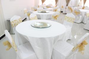 una fila de mesas y sillas con mantel blanco en Al Hussam Hotel Apartments, en Mascate