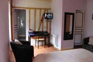 um quarto com uma cama, uma secretária e uma televisão em les agnates em Flagey-Échézeaux