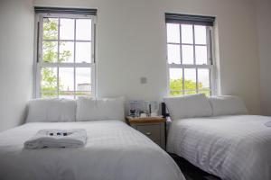 two beds in a room with two windows at Crofts Hotel in Cardiff