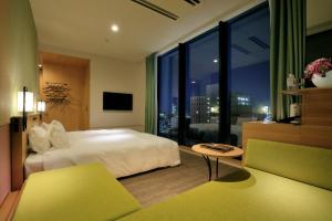 a hotel room with a bed, chair, and a television at Candeo Hotels Hiroshima Hatchobori in Hiroshima