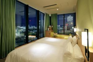 a bedroom with a large bed and a large window at Candeo Hotels Hiroshima Hatchobori in Hiroshima