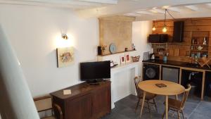 a kitchen with a table and a tv on a counter at Maison Camille in Port-en-Bessin-Huppain