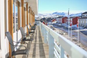a row of benches sitting on a balcony with a view at Hotel Hvide Falk in Ilulissat