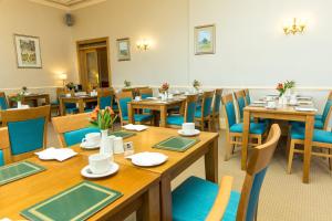 un comedor con mesas de madera y sillas azules en Mackays Hotel, en Wick