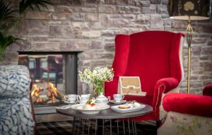 a living room with a red chair and a table and a fireplace at Dingle Skellig Hotel in Dingle