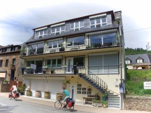 zwei Personen, die vor einem Gebäude Fahrrad fahren in der Unterkunft Appartements Moselblick in Klotten