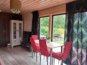 a dining room with red chairs and a table and a window at Parila Holiday House with Sauna in Parila