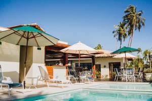 a pool with chairs and umbrellas next to a house at Hotel Fita Azul in Ilhabela