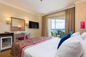 a hotel room with a bed and a desk and a television at Orange County Belek in Belek