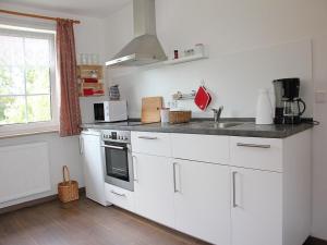 uma cozinha com armários brancos, um lavatório e uma janela em Ferienwohnung Die Fuchsmühle em Niedermeiser