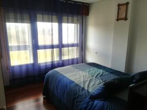 a bedroom with a bed with blue sheets and two windows at Las Mejores Vistas - The Best Views in Sopelana