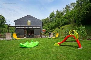 a yard with some playground equipment in the grass at Gîte les gadlis in Aywaille