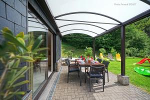 un patio con mesa y sillas bajo una pérgola en Gîte les gadlis, en Aywaille