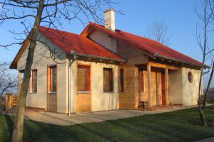 uma pequena casa de madeira com um telhado vermelho em Robiniapark em Szólád