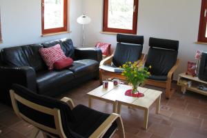uma sala de estar com um sofá de couro preto e cadeiras em Robiniapark em Szólád