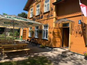 a building with benches and an umbrella outside of it at Portoss in Ventspils