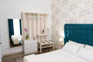 a bedroom with a blue headboard and a mirror at Liberty house in Siracusa