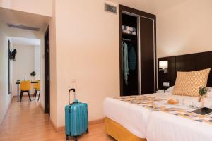 a hotel room with a bed and a suitcase at Aparthotel Ona Palamós in Palamós