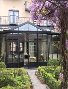 a glassconservatory with purple flowers in a garden at Hotel Ter Duinen in Bruges